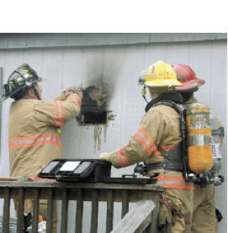 Firefighters from North Whidbey Fire and Rescue check the exterior of a modular home for hotspots following a kitchen fire Wednesday morning. North Fire Chief Marv Koorn said a resident of the Valley Mobile Home Park left a pan on the stove. When he returned
