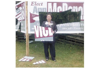 Ann McDonald stands next to one of her damaged signs in a photo she submitted. Other candidates have been reporting similar problems.