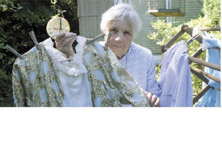 Mary Ellen Littke holds one of the elaborate gowns worn at special meetings for The Order of the Eastern Star. The symbol used to by the group is the star of Bethlehem.