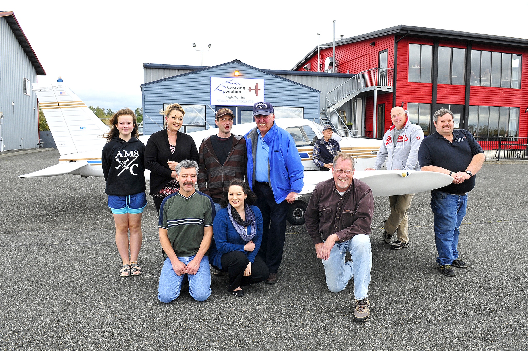 Photo by Michael Watkins/Whidbey News-Times                                Club members, owners and staff pose for a group photo in front of Cascade Aviation Saturday to celebrate its third year in business at the Skagit Regional Airport.