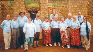 Volunteers from Trinity Lutheran stand in front of a brick and mortar building at the Watoto Village. From left to right