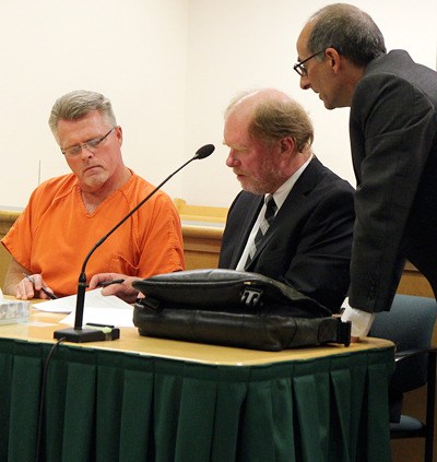 Bryan Ross signs paperwork in court Tuesday as attorney Craig Platt and Island County Prosecutor Greg Banks look on.