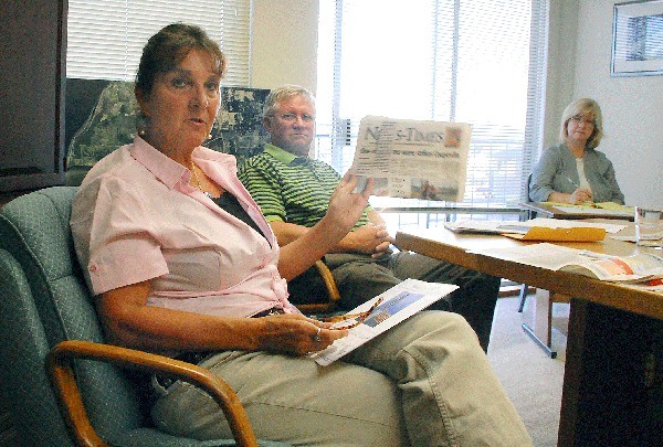 Newly appointed Oak Harbor Arts Commission member Peggy Darst Townsdin holds up a copy of the Whidbey News-Times during a Monday meeting at City Hall. She and local artist Wayne Lewis (center) are proposing a bronze sculpture to honor the city’s pre-settler past. Oak Harbor Administrative Assistant Karen Crouch is in the background.