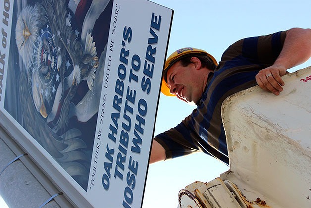 Jeff Rossi hangs a sign for the Walk of Honor project. He and his father