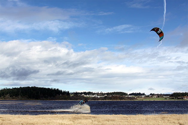A kiteboarder goes airborne on a gusty day on Crockett Lake in Coupeville last March. With winds picking up this month