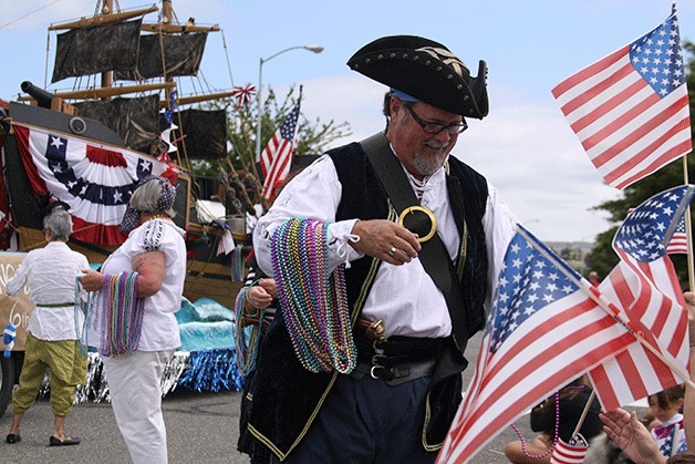 Buccaneer John Kingsbury hands out beads during the 2013 Fourth of July parade in Oak Harbor. The Oak Harbor Yacht Club group owns the popular pirate ship float.