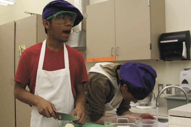 Jose Lupos chops an onion while classmate Nathan Yoast rinses his eyes in the culinary arts class at Oak Harbor High School. The school's culinary arts program will be preparing dishes for the Dutch Dinner April 25 in Oak Harbor. The event is a Holland Happening tradition that is being brought back.