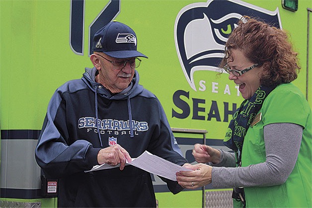 Sam Myers of Coupeville goes over paperwork with Penny Perka of Big Brothers Big Sisters of Island County the day after his name was drawn as winner of the Seahawks’ ‘Fanbulance.’