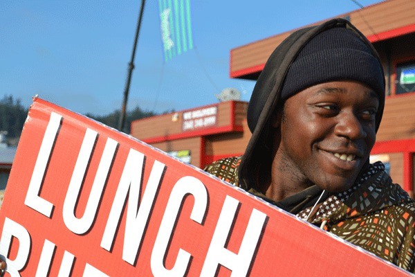 Demetrice Wall smiles and moves to the music while waving a sign at the corner of Pioneer Way and Highway 20.