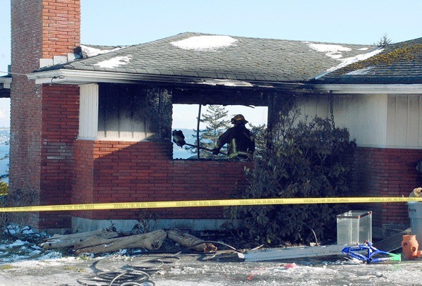 A North Whidbey Fire and Rescue firefighter sifts through the burnt shell of a Scenic Heights home along with investigators from the Island County Sheriff’s Office. The Monday evening blaze claimed the life of Dawn Campbell