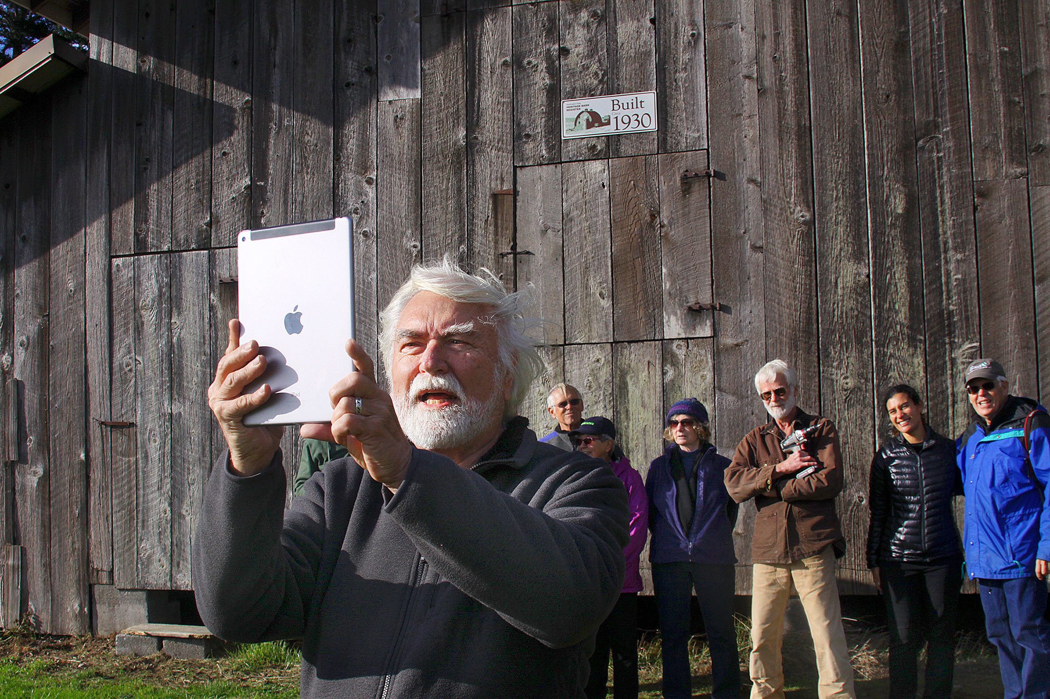 Harrison Goodall, front, takes a group photo in front of the Pratt Sheep Barn, which has been added to Washington’sHeritage Barn Register. The barn, located near the bluff on Ebey’s Prairie, was restored by Goodall and a group ofvolunteers three years ago.