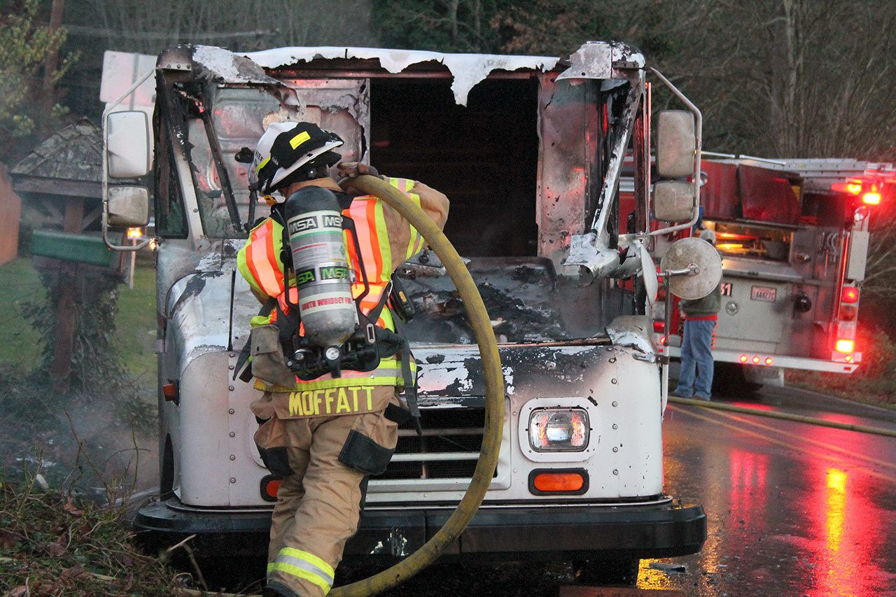 Photo by Kyle Jensen / The South Whidbey Record                                South Whidbey Fire/EMS Deputy Chief Wendy Moffatt douses the flames in a mail truck in Freeland Wednesday. A fuel leak was suspected as the cause.