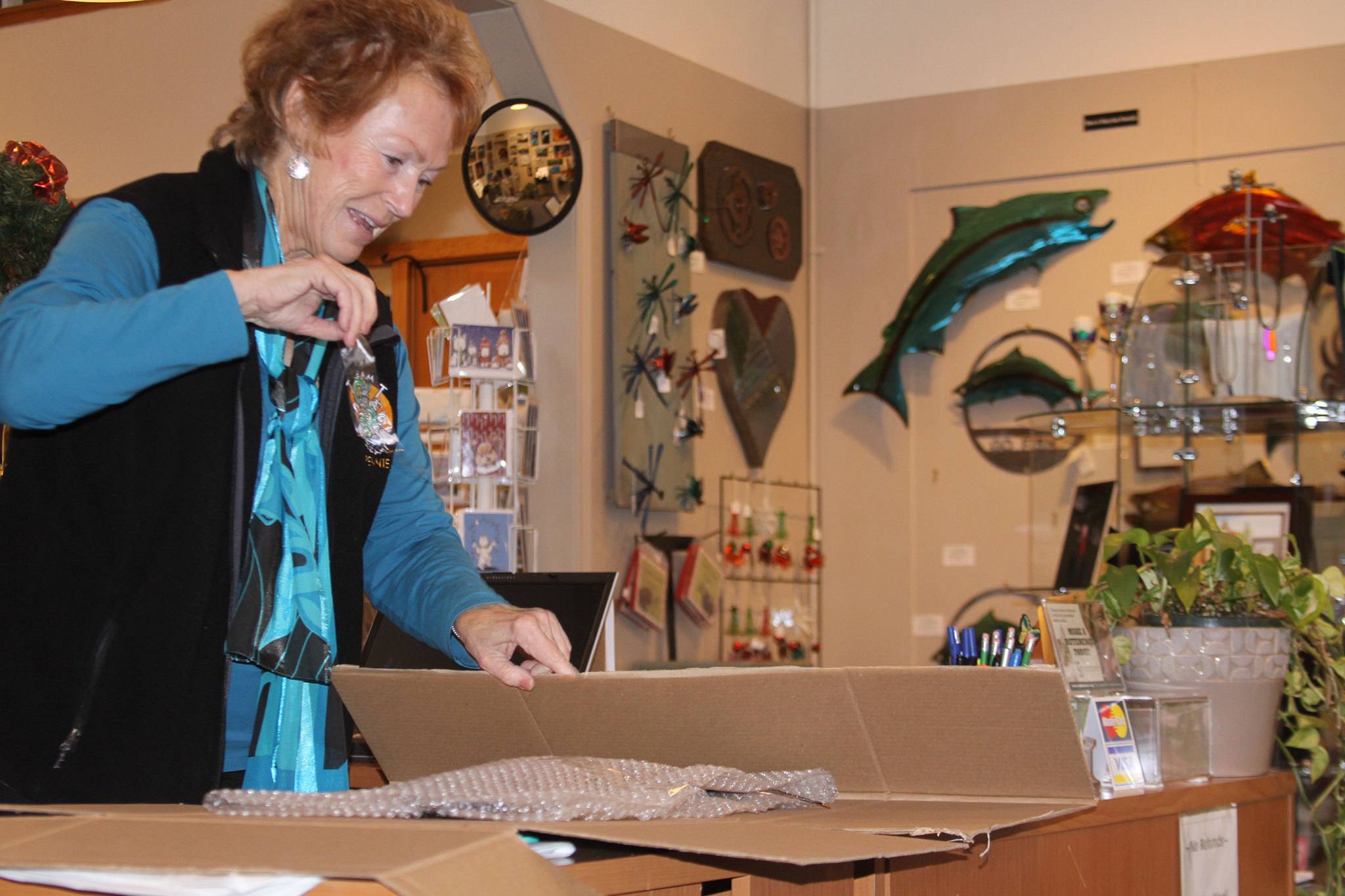 Pennie Allison Rees, a Coupeville watercolor artist, boxes up a customer’s purchase of one of the salmon created by Oak Harbor metalworks artist Steve Nowicki Thursday, Dec. 1, at Garry Oak Gallery in Oak Harbor. Photo by Ron Newberry/Whidbey News-Times