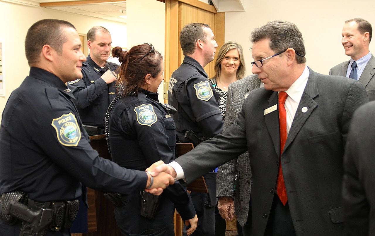 Photo by Jessie Stensland/Whidbey News-Times                                Oak Harbor Mayor Bob Severns shakes hands with Officer Michael Brown, who was recognized Tuesday for helping to catch the Cascade Mall shooting suspect. The mayor and council members also thanked Officer Mike Clements and Officer Claire Schricker for saving a man who was in a medical crisis.
