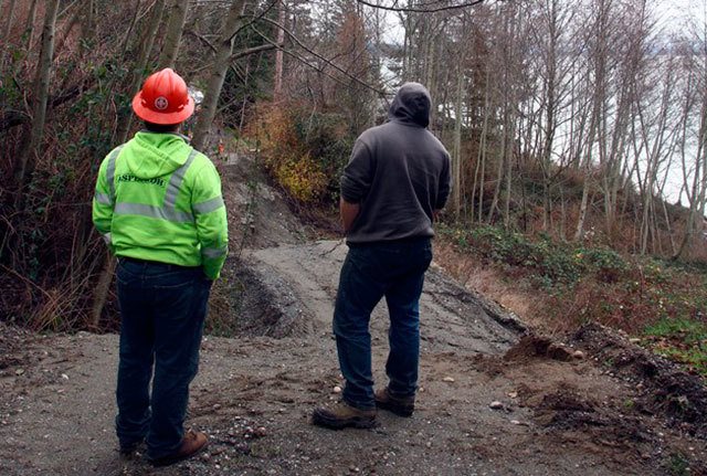 Workers survey a section of Driftwood Way that was destroyed in the 2013 landslide. The county budgeted to fix the road next year.