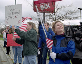 Victoria Rice looks up at the flag during an Oak Harbor rally to support U.S. troops in the Middle East. She helped put together Wednesday afternoon’s rally the previous night after watching the news