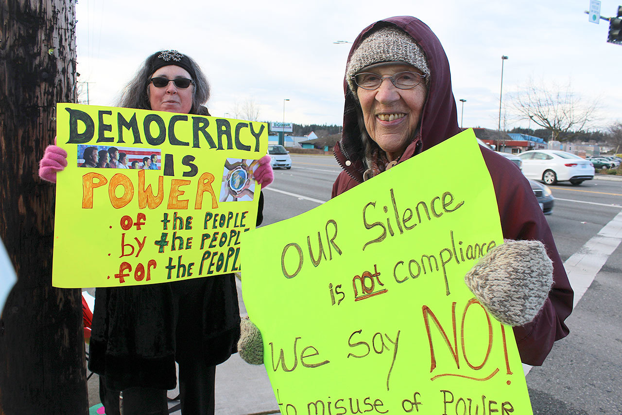 Melissa Duffy, left, from Oak Harbor and Herta Kurp from Anacortes, right, comprised a two-woman protest on the corner of State Route 20 and Whidbey Avenue in Oak Harbor Friday as Donald Trump was sworn in as the 45th president.                                Photo by Patricia Guthrie/Whidbey News-Times