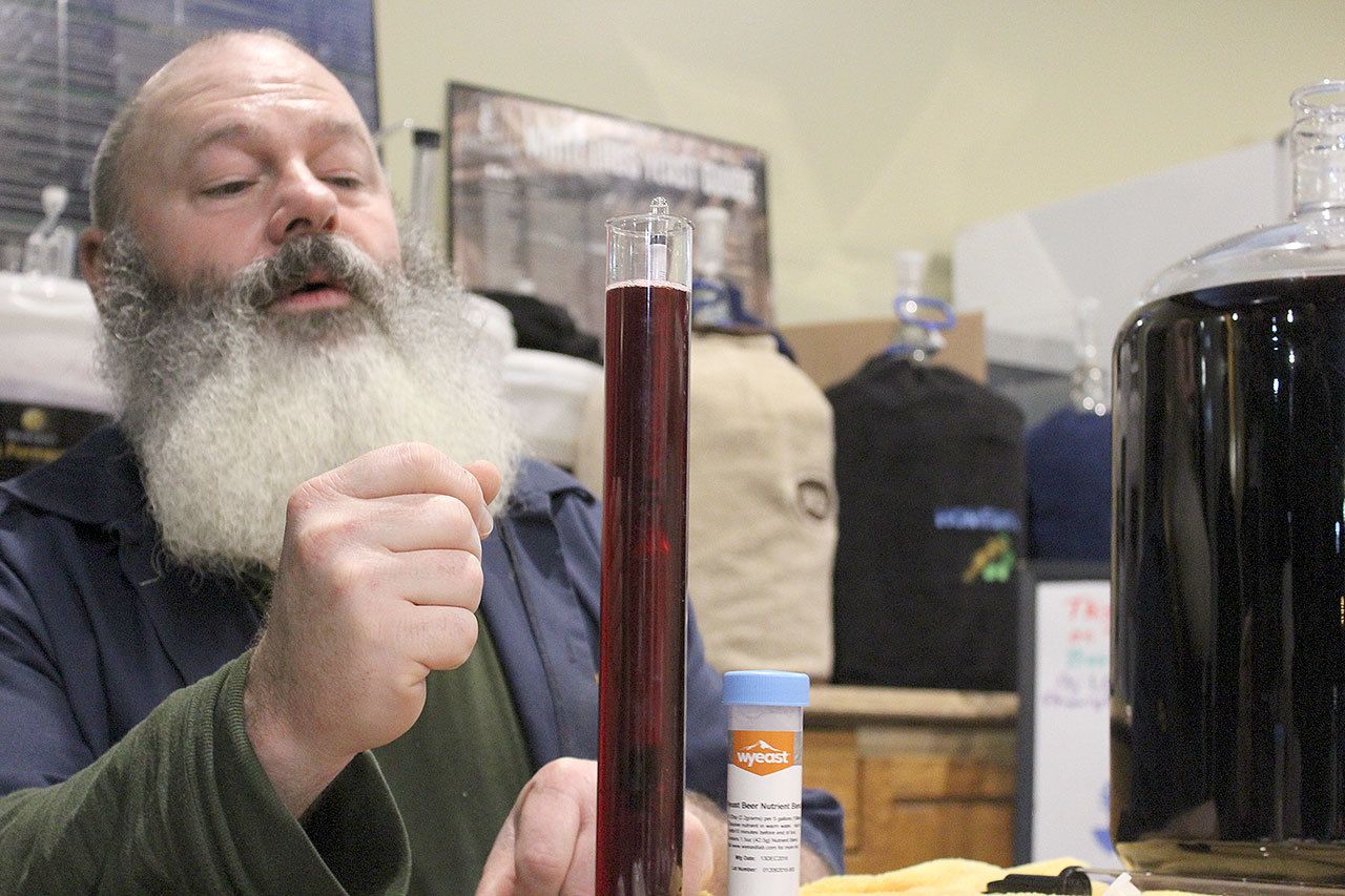 Terry Boese checks how a batch of elderberry wine is aging at his Oak Harbor store, Whidbey Island Homebrew Supply.                                Photo by Patricia Guthrie/Whidbey News-Times