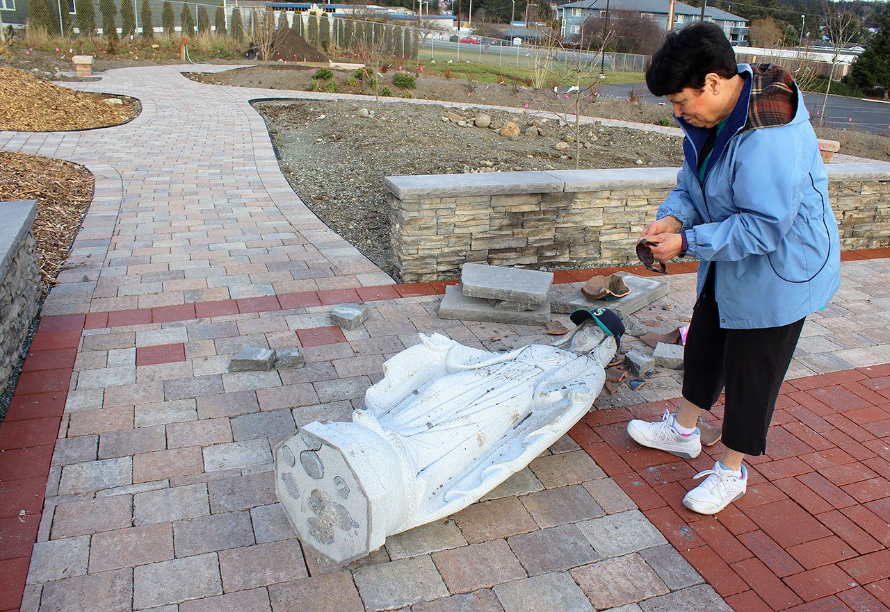 Theresa Frazer looks over the damage to the Mary statute at St. Augustine Catholic Church in Oak Harbor. Wednesday night, vandals knocked over the 5-foot tall granite statute that’s the centerpiece of the new Prayer Garden. Photo by Patricia Guthrie/Whidbey News-Times