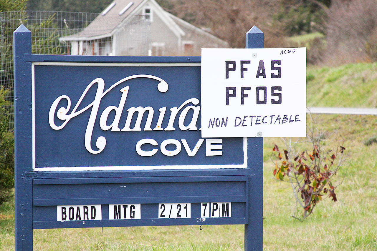 A sign mounted to an entrance sign to Admiral’s Cove reveals good news Friday, March 3, 2017 for residents awaiting test results from water samples taken from their community wells last month: No contaminants were detected. In the background, outside of Admiral’s Cove, is a guesthouse on property where contaminants were found in a private well. Photo by Ron Newberry/Whidbey News-Times