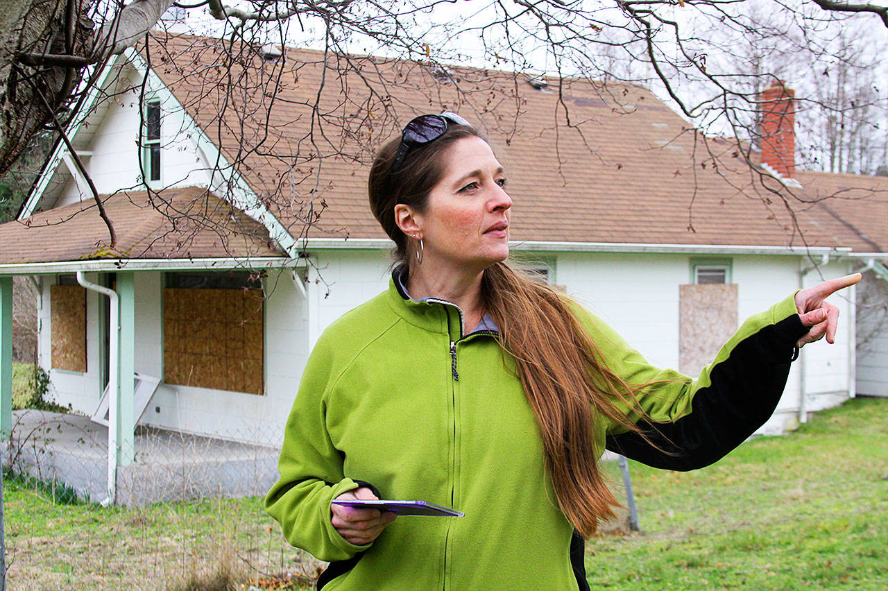 Kendall Campbell, archaeologist and cultural resource program manager at Naval Air Station Whidbey Island, points out features at two of the historic farmhouses near Ault Field that are slated for demolition unless they are moved from the property. Photo by Ron Newberry/Whidbey News-Times