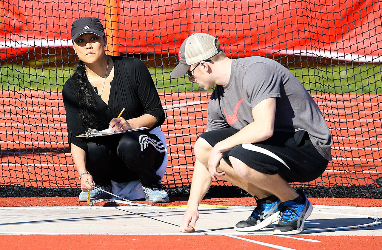 Eileen Stone, left, and Dalton Martin help out with the discus in Thursday’s meet. (Photo by John Fisken