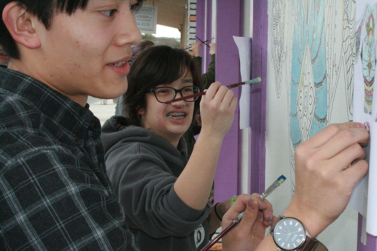 Students Ronald Eborda, left, and Cassandra McLeod paint a mural with the rest of The Guild, Oak Harbor High School’s student art club, earlier this month. The mural is located on the exterior wall of the Sweet Rice restaurant on Pioneer Way in Oak Harbor. Photo by Daniel Warn/Whidbey News-Times