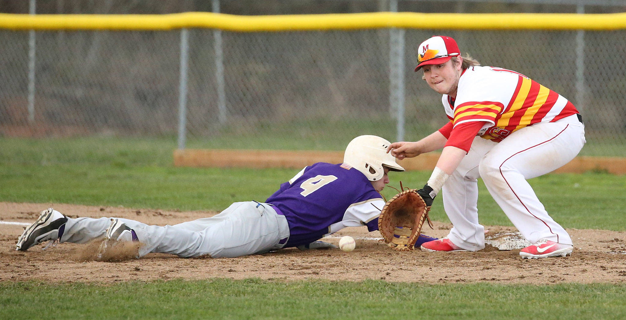 Oak Harbor&rsquo;s Steven Richards dives safely back to first base as Marysville-Pilchuck&rsquo;s Kyler Alvis awaits the pickoff throw. (Photo by John Fisken)