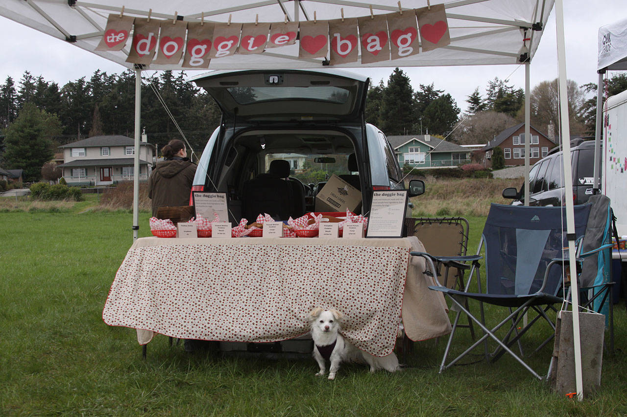 A pooch stands guard at “the doggie bag” booth Saturday at the opening day of the Coupeville Farmers Market. The booth offers edible treats for man’s best friend. The market takes place from 10 a.m. to 2 p.m. every Saturday except Aug. 12 through mid-October. Photo by Ron Newberry/Whidbey News-Times