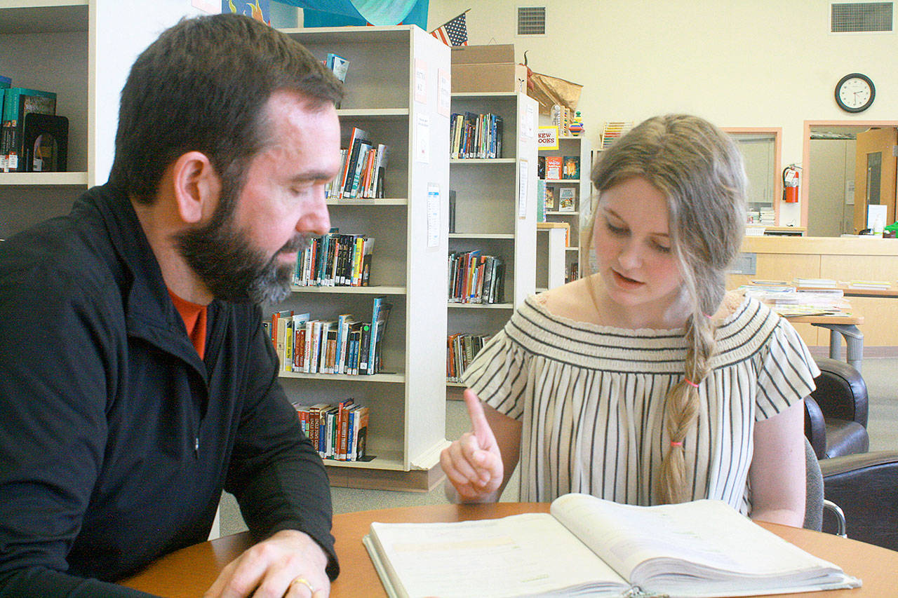 HomeConnection freshman Michelle Consolver studies her math textbook, while principal Shane Evans looks on, ready to help. Photo by Daniel Warn/Whidbey News-Times