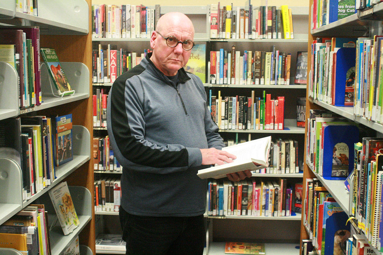 Poet Daniel Moore peruses books Wednesday at Oak Harbor Library, a member of Sno-Isle Libraries, which will sponsor a poetry reading of Moore’s next month in Coupeville. Photo by Daniel Warn/Whidbey News-Times