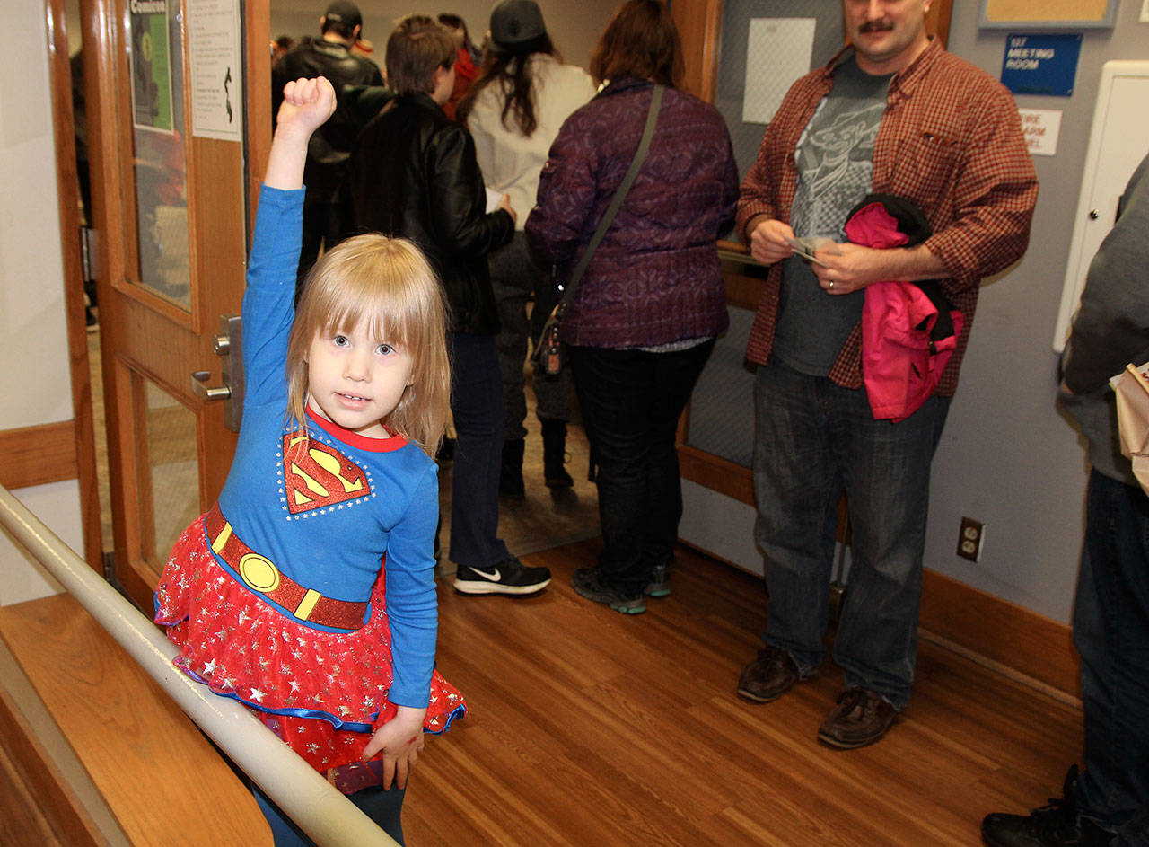Katrina Daggett, Supergirl, strikes a pose at Oak Harbor Library’s comicon, which neared 400 attendees Saturday in it’s first year. Her father, Steve Daggett, looks on with pride from behind.                                Photo by Daniel Warn/Whidbey News-Times