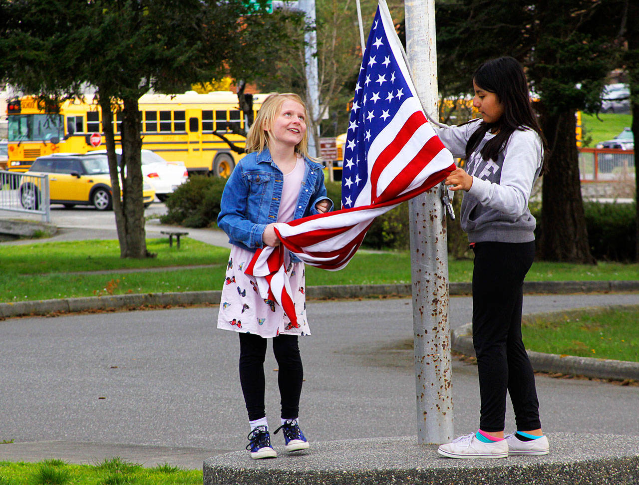 Coupeville Elementary School fifth graders May Crain, left, and Desi Ramirez-Vasquez take down the flag at the end of the school day March 31, 2017. The Coupeville School District is exploring options as it looks at long-range planning for the aging elementary school. One option is to build a new school away from the busy highway. Photo by Ron Newberry/Whidbey News-Times