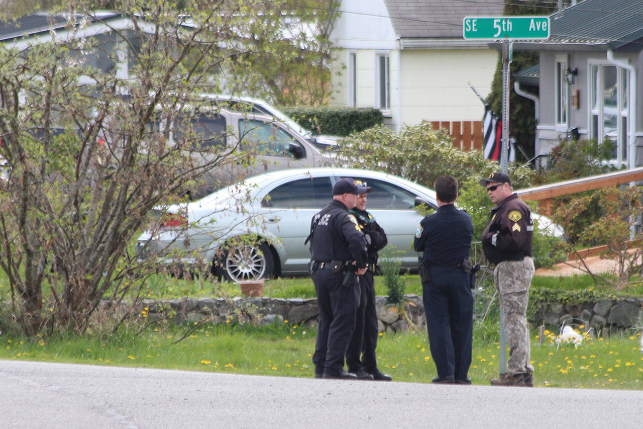 Oak Harbor police officers talk near the site of a standoff Wednesday. (Jessie Stensland / Whidbey News-Times)