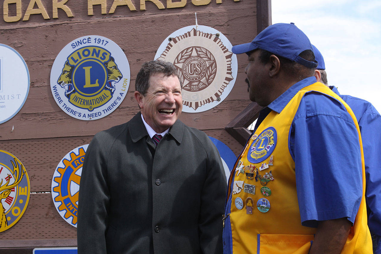 Oak Harbor Mayor Bob Severns, left, visits with Oak Harbor Lion James House in front of the city’s welcome sign that also features the emblems of the community’s service organizations. The Oak Harbor Lions celebrated the centennial anniversary of their parent club, Lions Clubs International, by installing a new emblem. Photo by Ron Newberry/Whidbey News-Times
