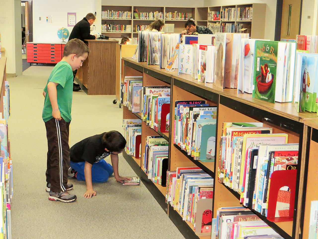 Casey Cook, left, and a fellow Crescent Harbor Elementary student peruse the books at the school’s library. According to school librarian Bill Montross, 98 percent of the library’s approximate 14,000 offerings are included in the Accelerated Reader program. Photo provided