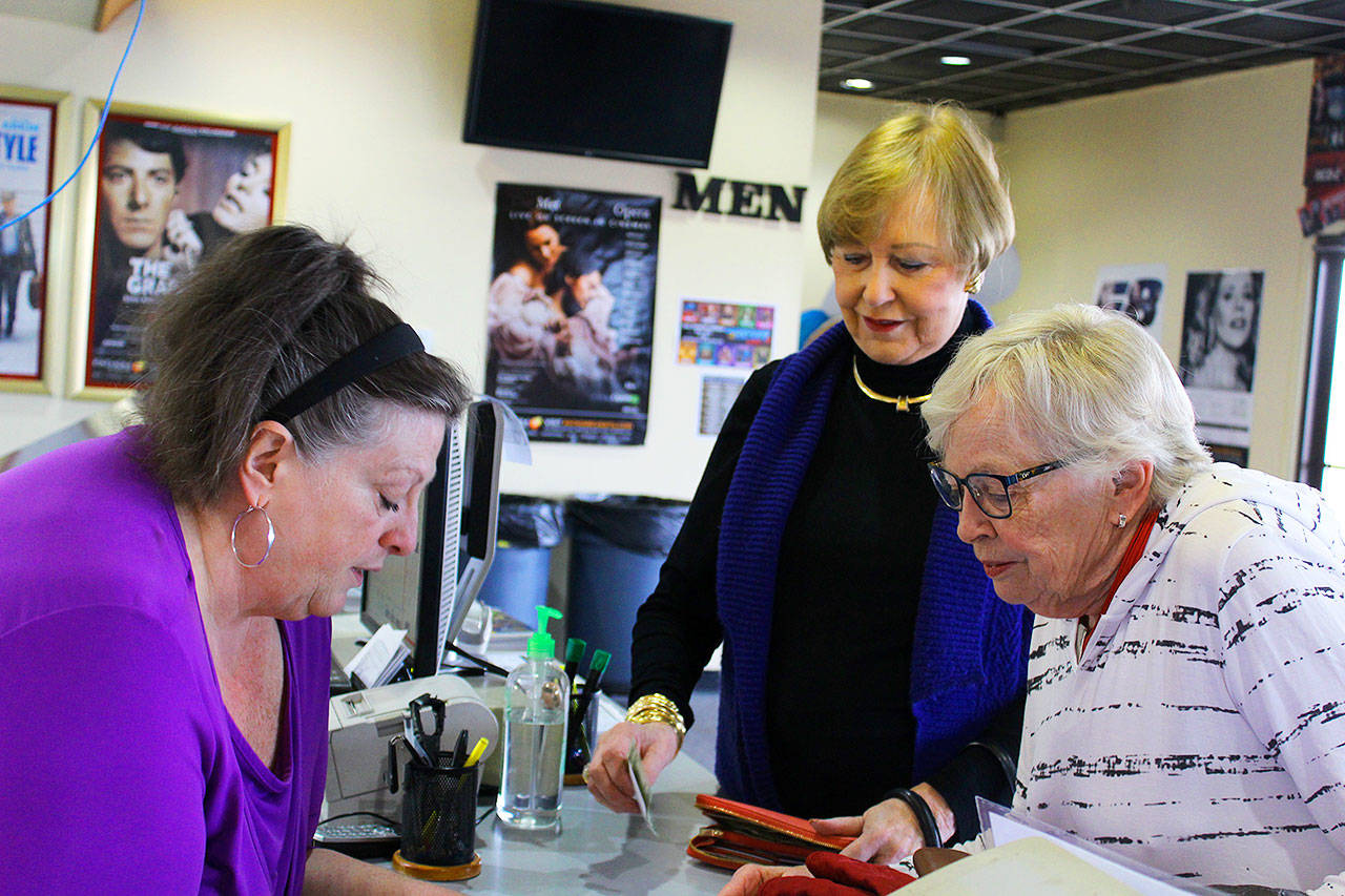Oak Harbor Cinemas manager Rita LaBelle (left) looks over the Metropolitan Opera schedule with her “opera people” Clare Christiansen (center) and Carole Lafond before a Saturday performance.Photos by Patricia Guthrie/Whidbey News-Times