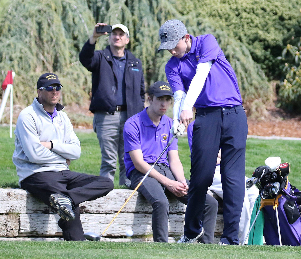 With coach David Smith looking on, Nate Thompson tees off for the Wildcats. (Photo by John Fisken)