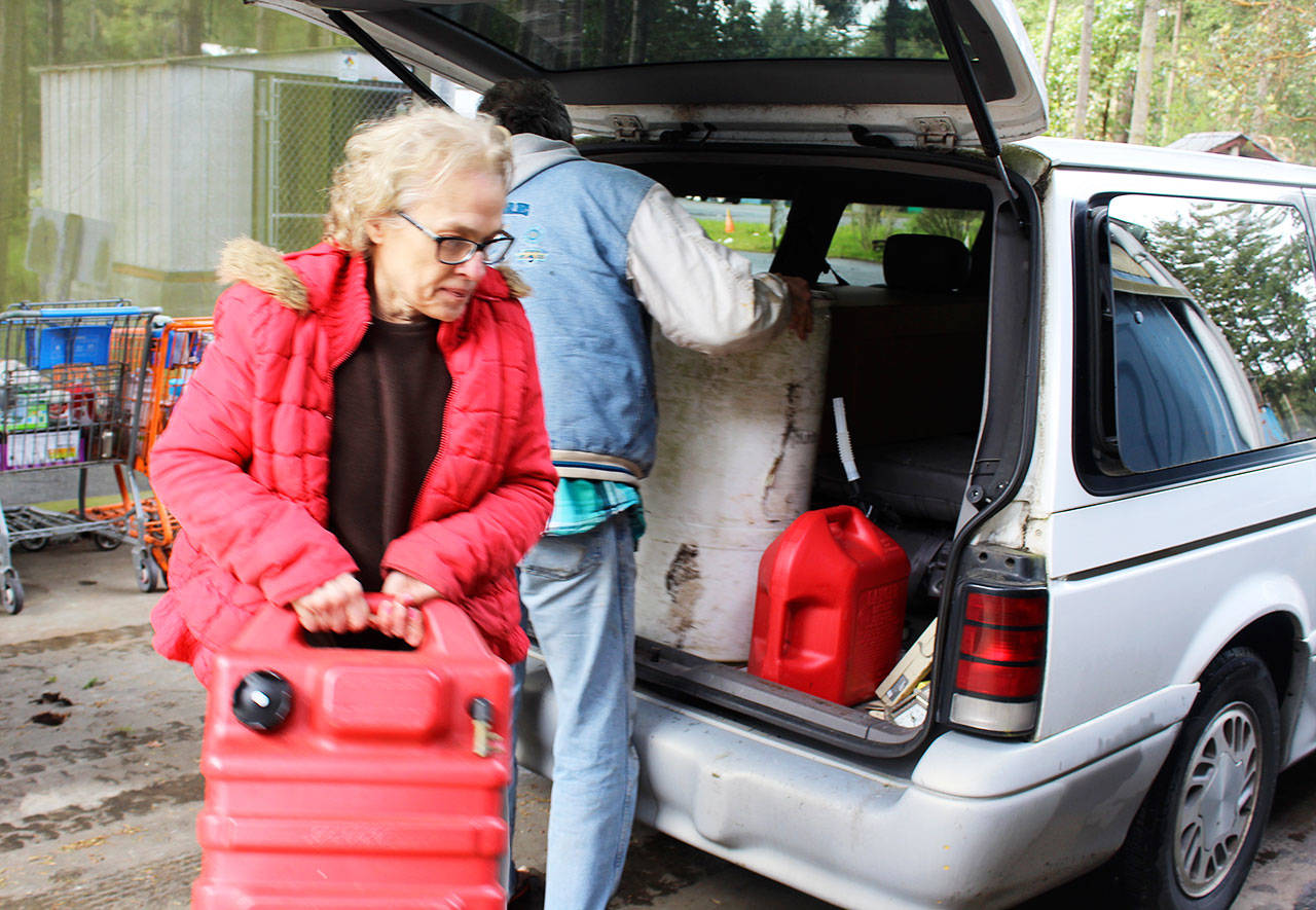 Freeland residents, Bob Brower and Debra Whitson, get help disposing of 90 gallons of gasoline that had been sitting on a fishing boat they just purchased. Photo by Patricia Guthrie/Whidbey News-Times
