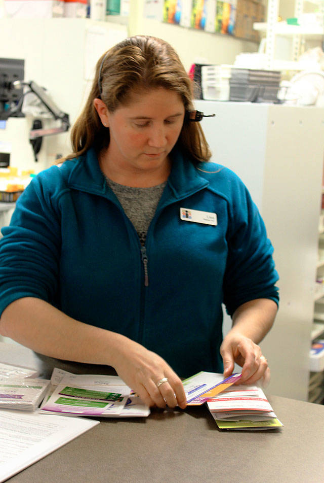Island Drug pharmacy tech Lisa Bacolo sorts through the many prescription cards customers bring in but the one offered by the county is not among them. Photo by Patricia Guthrie/Whidbey News-Times