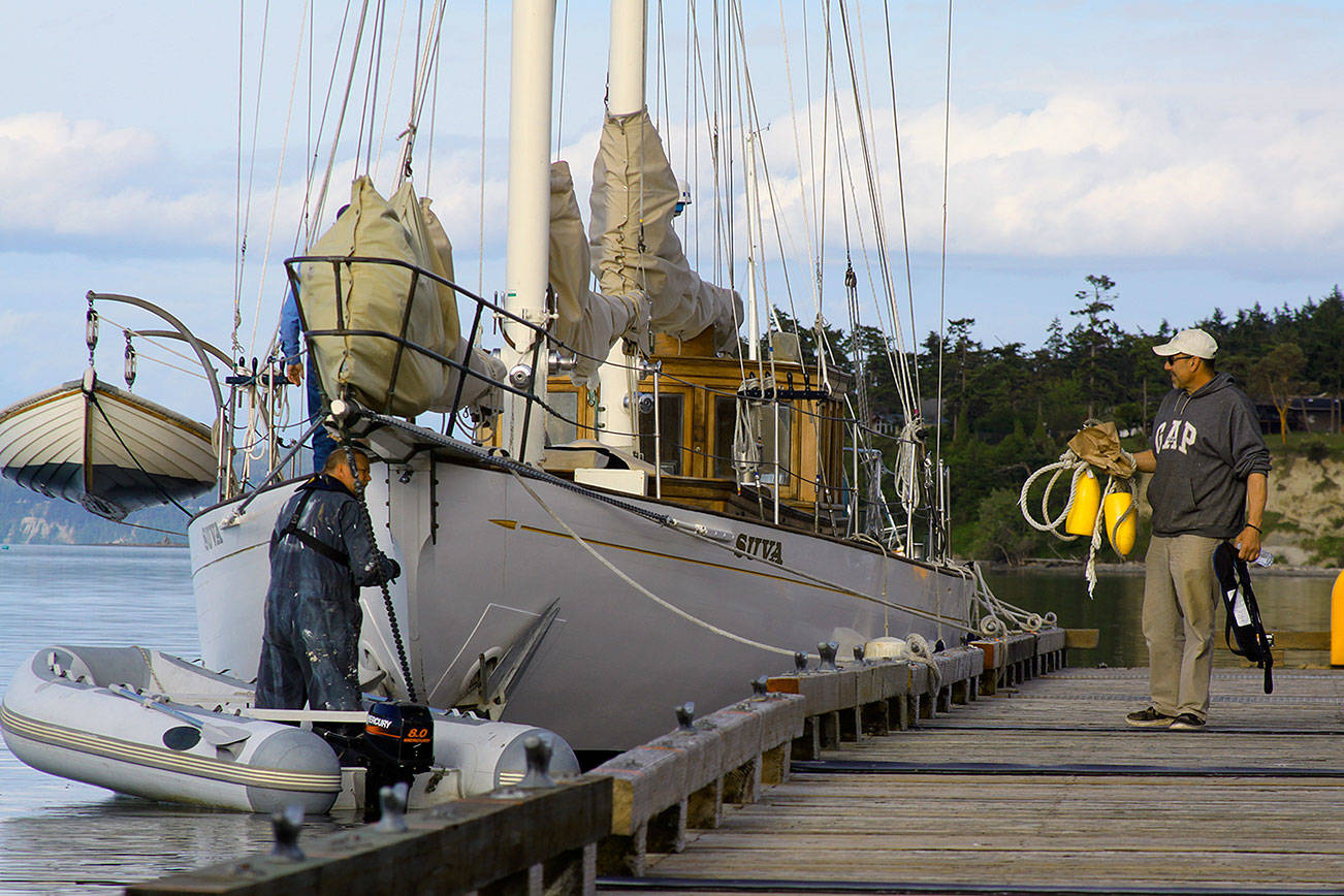 Mark Saia, right, chats with fellow captain Jonny Johnson before departing the Coupeville Wharf Wednesday. A night earlier, the 1925 schooner Suva broke free from her mooring during a nasty wind storm and ended up approaching the rocks across Penn Cove near Blowers Bluff. Saia got in an inflatable tender at the wharf and raced across the cove despite heavy gusts, high waves and increasing darkness to single-handedly rescue the boat. Photo by Ron Newberry/Whidbey News-Times