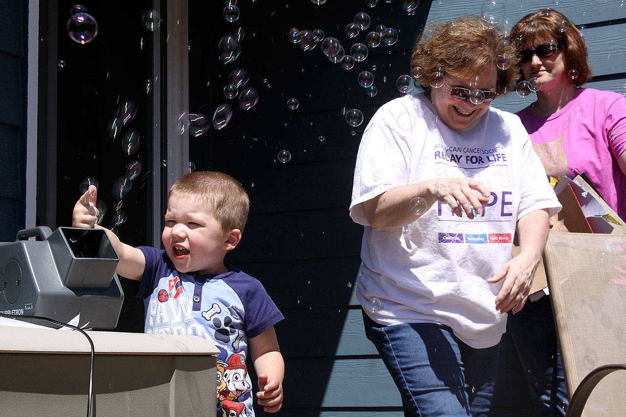 Jackson Young, 3, tries out the bubble machine while Mary Brock, center, and Wendy Hermandorfer try to stand clear of the bubbles Sunday at Karla Sharkey’s house in Oak Harbor Sunday. The group met for some final preparations for Relay for Life of Whidbey Island, which starts at 6 p.m. Friday. The bubbles will glow in the dark after Friday night’s luminary ceremony. Photo by Ron Newberry/Whidbey News-Times