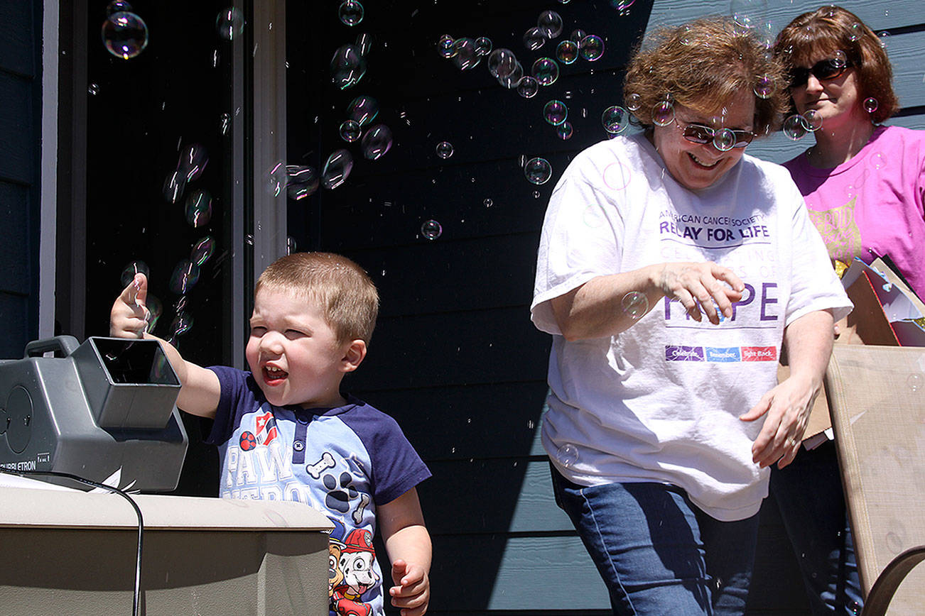 Jackson Young, 3, tries out the bubble machine while Mary Brock, center, and Wendy Hermandorfer try to stand clear of the bubbles at Karla Sharkey’s house in Oak Harbor Sunday. The group met for some final preparations for Relay for Life of Whidbey Island, which starts at 6 p.m. Friday. The bubbles will glow in the dark after Friday night’s luminary ceremony. Photo by Ron Newberry/Whidbey News-Times