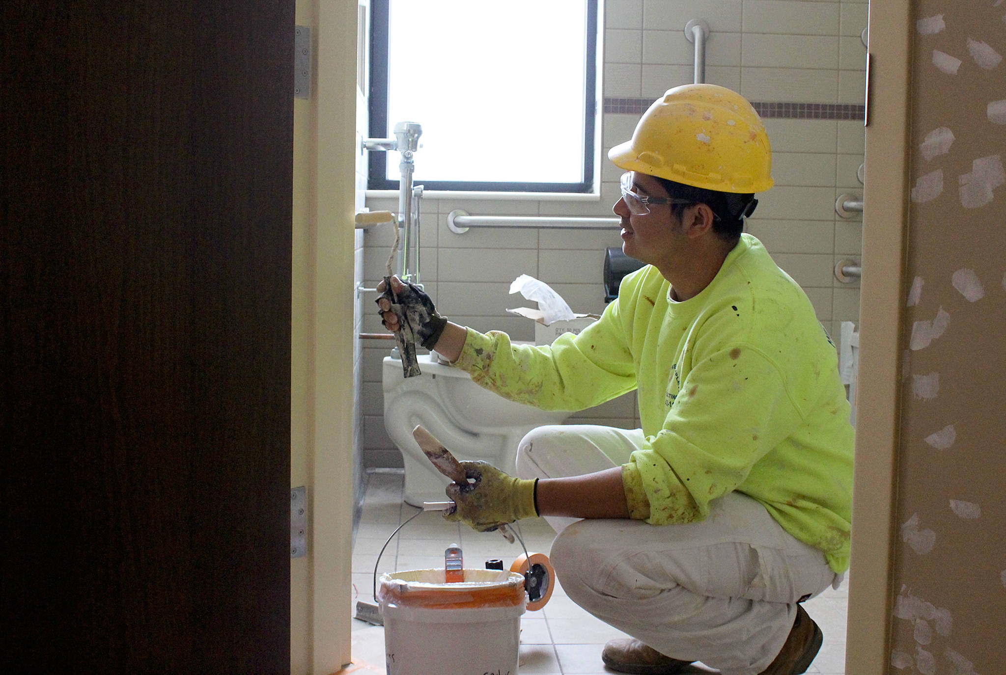 Working on the finishing touches of a patient room inside the new wing of WhidbeyHealth Medical Center, Carlos Torres paints a bathroom door. The 39-room wing is slated to open July 7. Photo by Patricia Guthrie/Whidbey News-Times