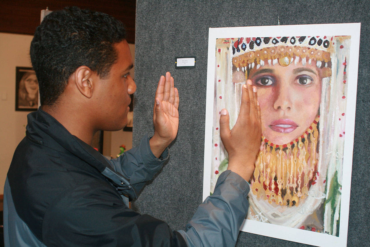 Oak Harbor art student Julian Mata describes all the strengths in Marie Kelley’s oil painting, “Preservation,” at Christian Reform Church’s annual high school art show last month. Photo by Daniel Warn/Whidbey News-Times