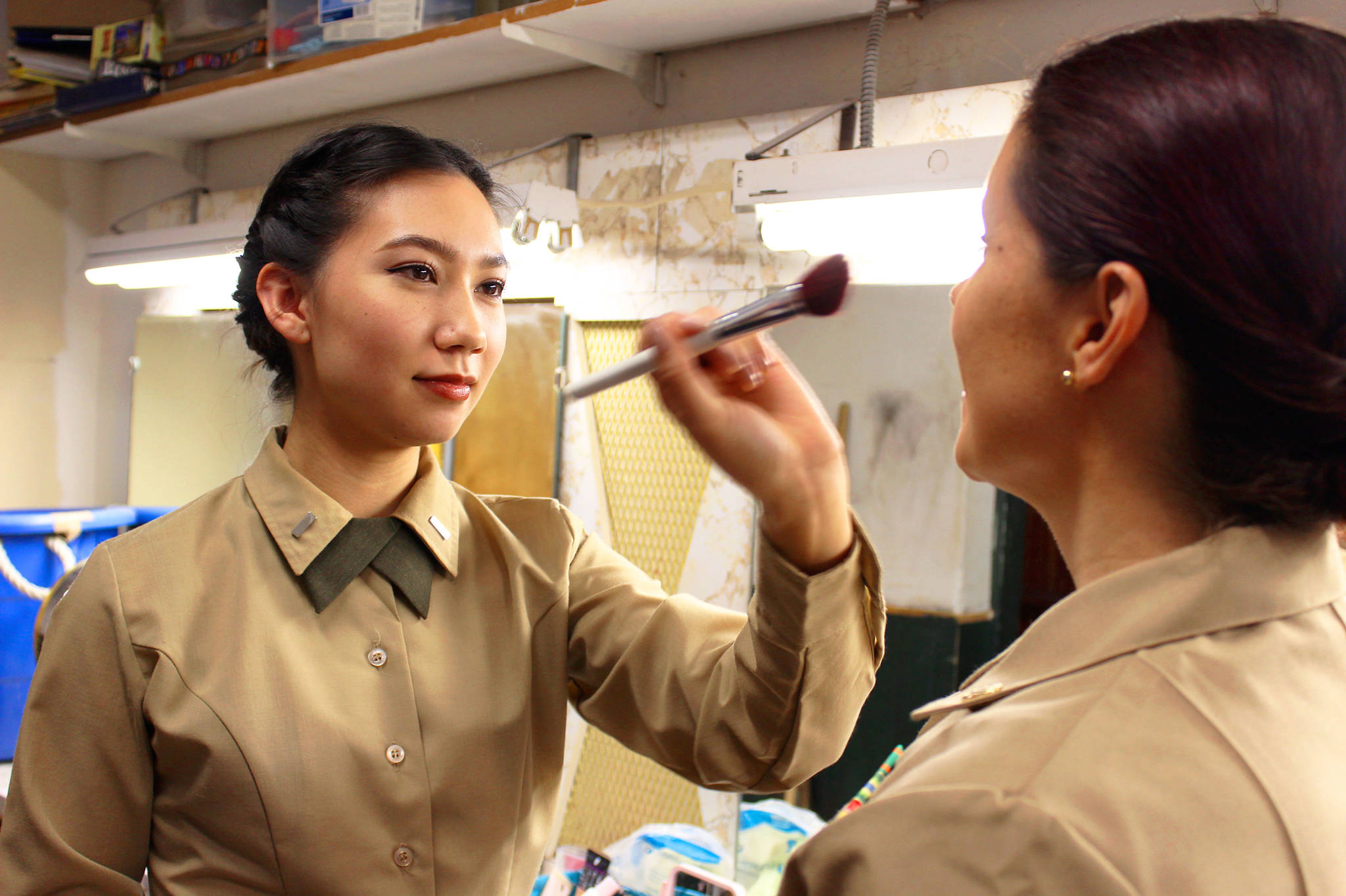Moriah Sittner applies powder to the face of Tara Hizon before a rehearsal of “A Few Good Men” at Whidbey Playhouse in Oak Harbor. The actresses play lead characters in the military drama that is set in Guantanamo Bay, Cuba.                                Photo by Patricia Guthrie/ Whidbey News-Times