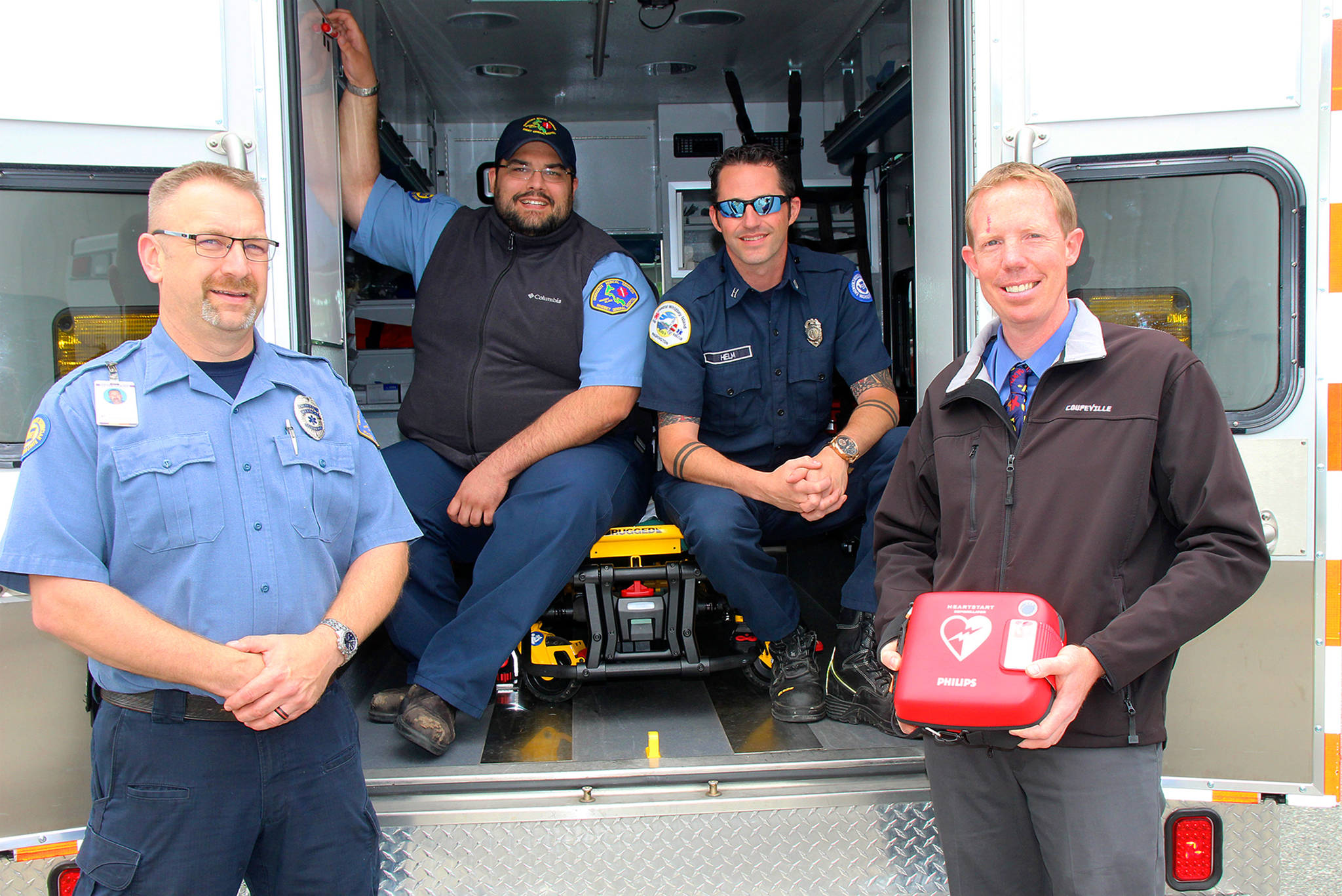 Coupeville teacher and South Whidbey firefighter Jon Gabelein, far right, meets with first responders whom he says represent collaboration among agencies on the island. Gabelein was recently involved in helping to save a woman using an AED, one of which he is holding. From left are Gregory Behan, an EMT with WhidbeyHealth, Scott Jackson, a paramedic, and Capt. Jerry Helm with Coupeville Fire & Rescue.