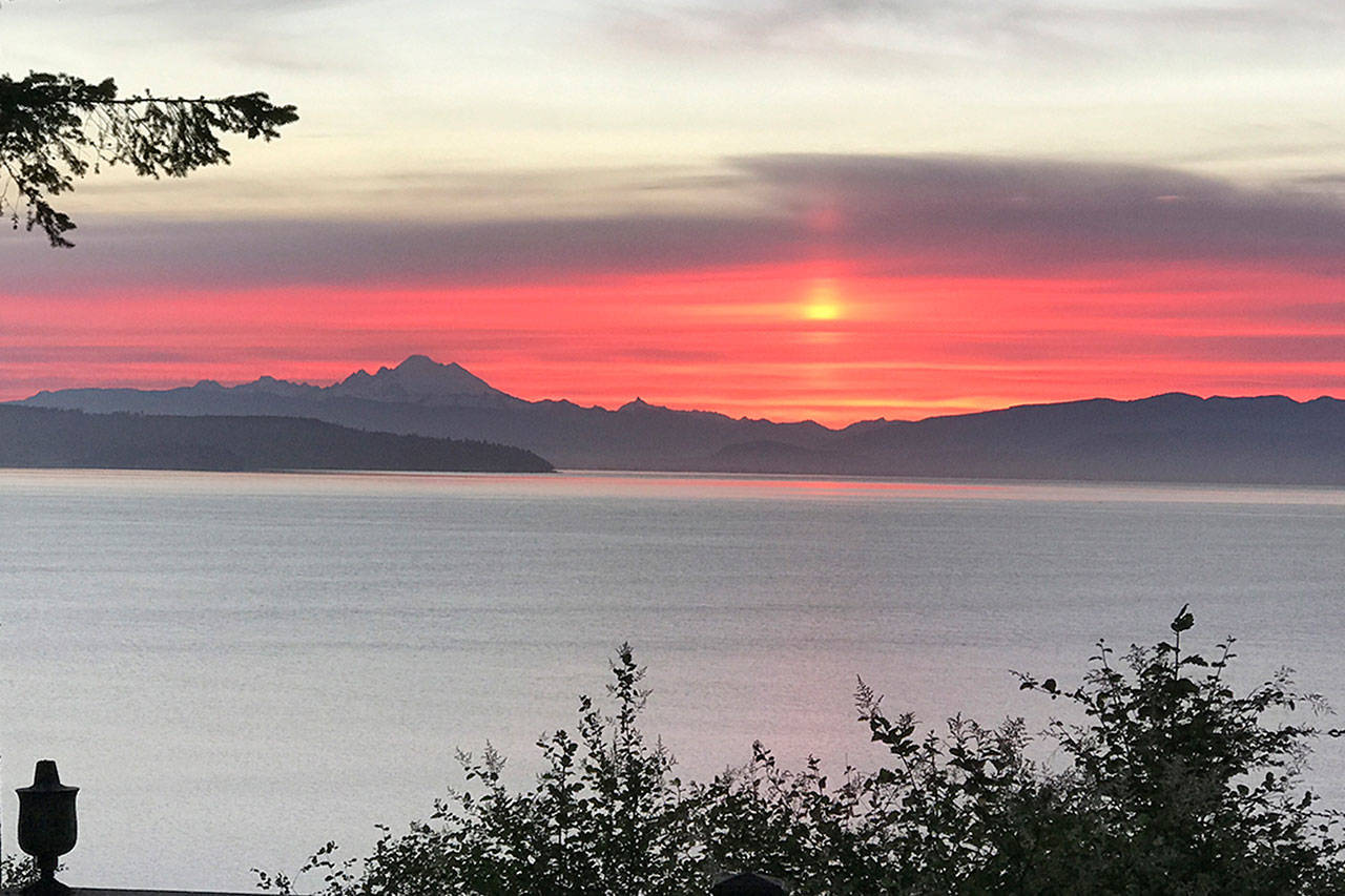 The sunrise splashes pink hues upon the sound June 6, as seen from Rhodena Beach in the direction of Mount Baker. Photo by Gregg Thomas
