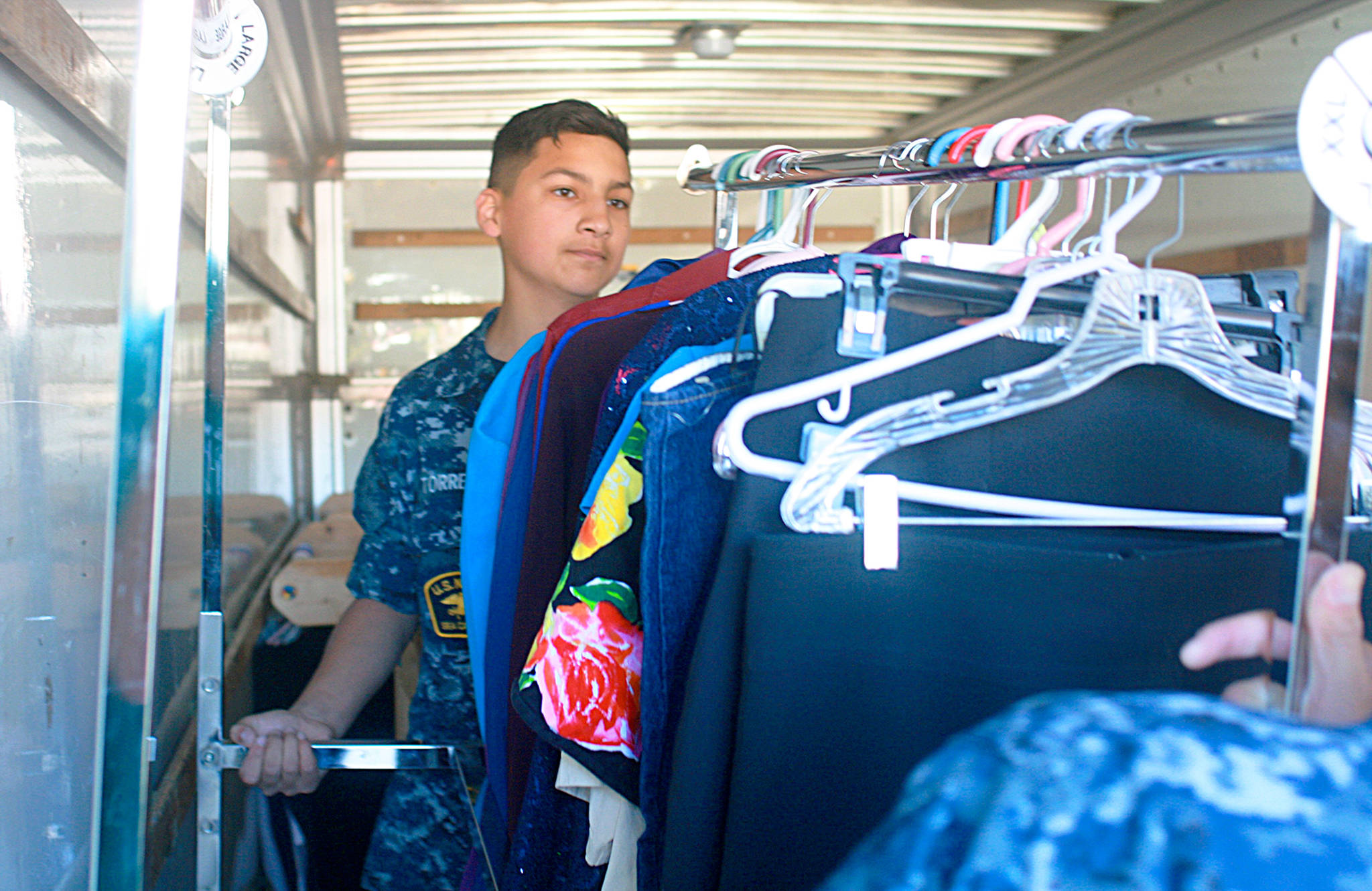 Sea Cadet Isidro Torres, 13, helps move a rack of clothing into a moving truck for Garage of Blessings Friday. The nonprofit has moved to 1751 N. Goldie Road, Oak Harbor. Photo by Daniel Warn/Whidbey News-Times