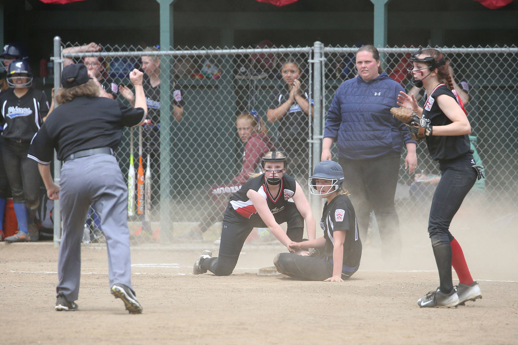 Umpire Rita Cline calls out an Orcas Island runner at third base as Audrianna Shaw applies the tag and Coral Caveness looks on. (Photo by John Fisken)